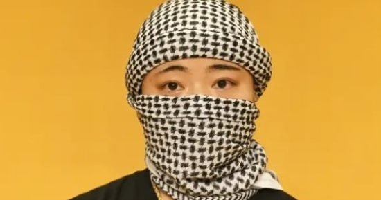 كاتبة يابانية ترتدى الكوفية وعلم فلسطين أثناء تتويجها بجائزة أدبية